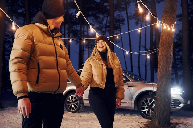 Automobile parked behind Couple standing in the forest and celebrating New year