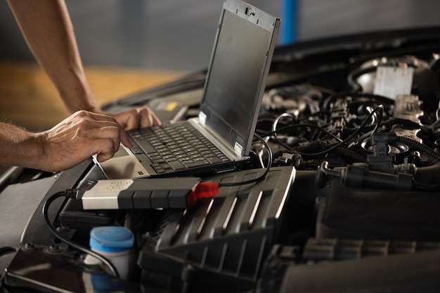 Automobile service car mechanic auto mechanic uses a laptop while conducting diagnostics test