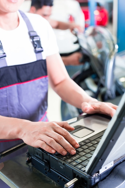 automonteur auto-motor met diagnosetool in zijn werkplaats controleren