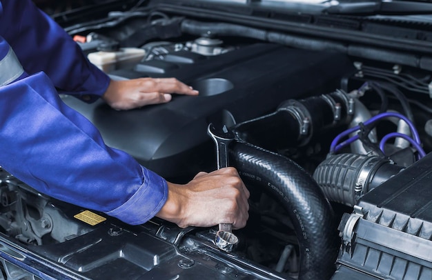 Automonteur bezig met automotor, auto-onderhoudsconcept.