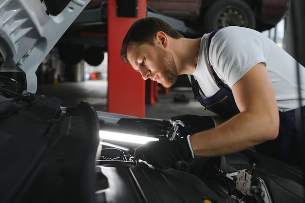 Automonteur bezig met automotor in monteurs garage Reparatieservice