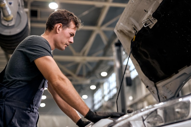Automonteur bij het doen van autoreparatieservice en onderhoudsmedewerker die voertuigservice en -onderhoud repareert