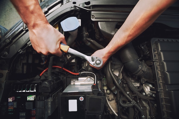 Automonteur die aan de motor van een auto werkt met gereedschap