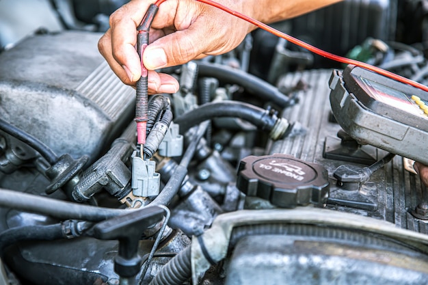 Automonteur die elektrisch systeem in een automotor controleert.