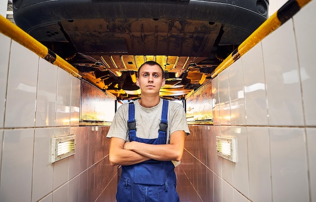 Automonteur die het loopwerk van de auto controleert op het tankstation Mannelijke werknemer die het probleem met het auto-onderhoudsconcept oplost