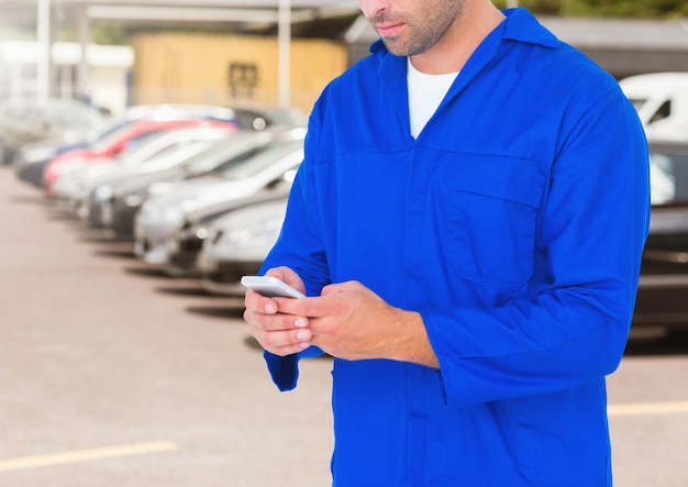 Automonteur die mobiele telefoon gebruikt tegen geparkeerde auto