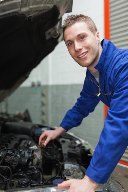 Automonteur die motor van een autoolie controleert