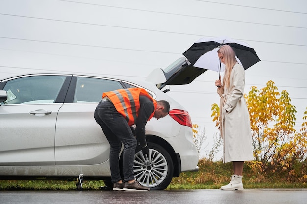 Automonteur die vrouwenauto op de weg herstelt