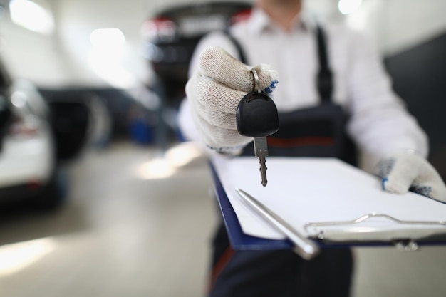 Automonteur houdt klembord en autosleutels vast