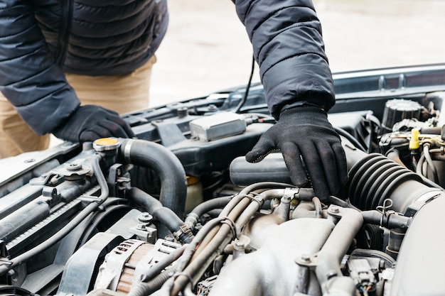 Automonteur-ingenieur tot vaststelling van auto, waardoor onderhoud uitgebreide automatische controle. Automonteur in handschoenen ontdekte storing in autoreparatiedienst.