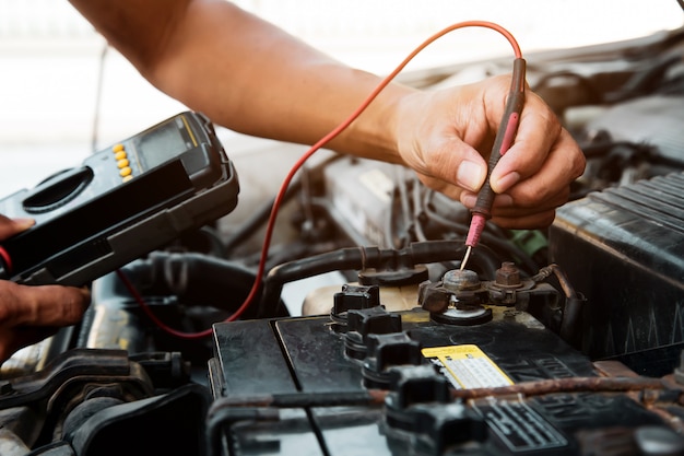 Automonteur met behulp van meetapparatuur tool auto accu controleren.