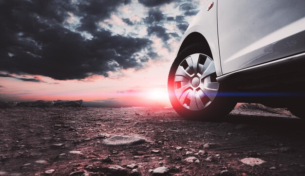 Autoreizen en avontuur. Gesloten beeld van autowielen en banden op de grond en avondrood