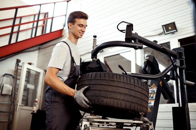 Autoreparatieservice en -onderhoud: een jonge man is aan het werk om een band te repareren.