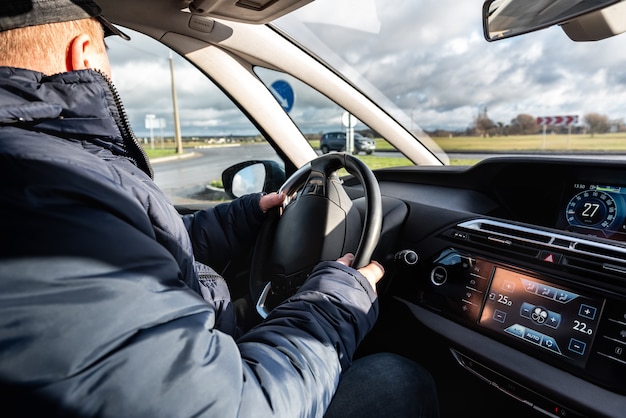 Autorijden Een man die achter het stuur van een auto zit en het stuur vasthoudt