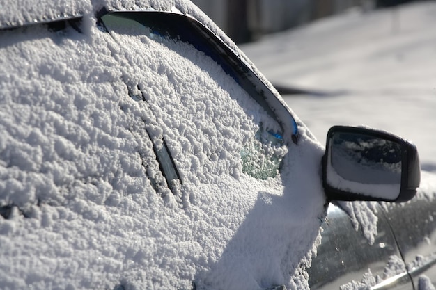 Autoruiten zijn bedekt met een laag sneeuw Close-up van de auto na een sneeuwstorm