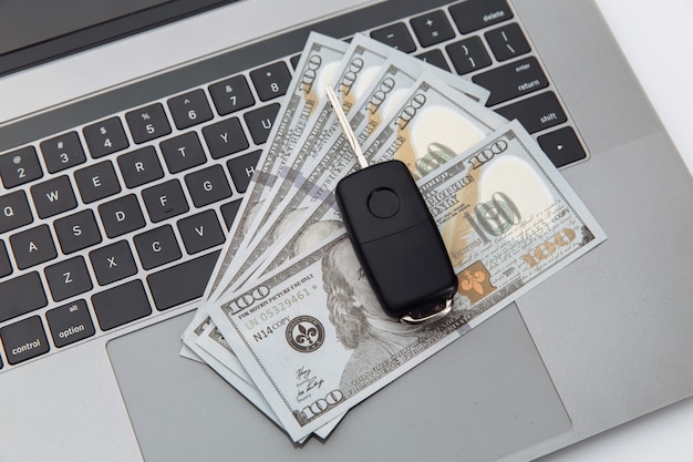 Autosleutel en geld op laptop. Online aankoop auto concept