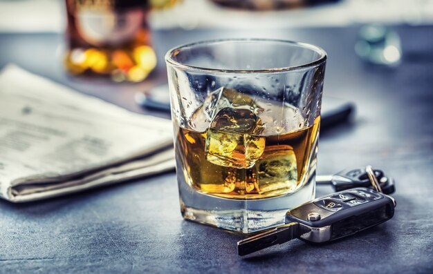 Autosleutels en glas alcohol op tafel in pub of restaurant.