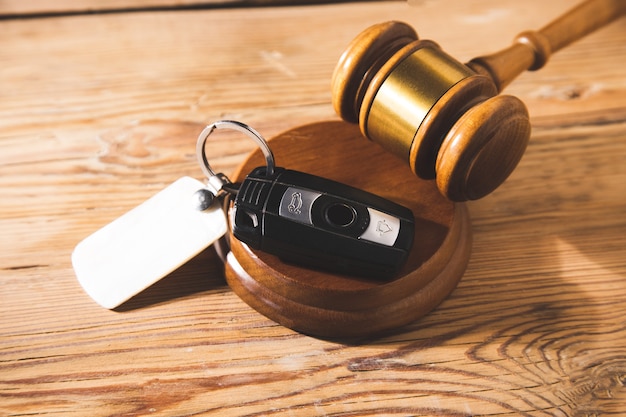 Autoveilingconcept - hamer en autosleutel op het houten bureau