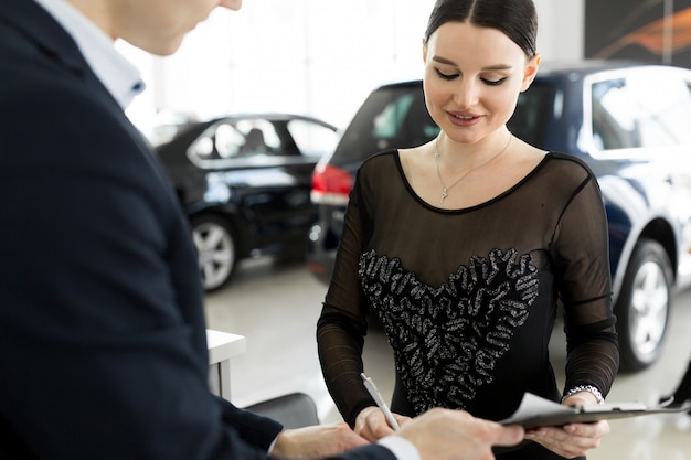 Autoverhuur en verzekeringsconcept, jonge verkoper die geld ontvangt en de sleutel van de auto aan de klant geeft na ondertekeningsovereenkomst met goedgekeurde deal voor huur of aankoop.