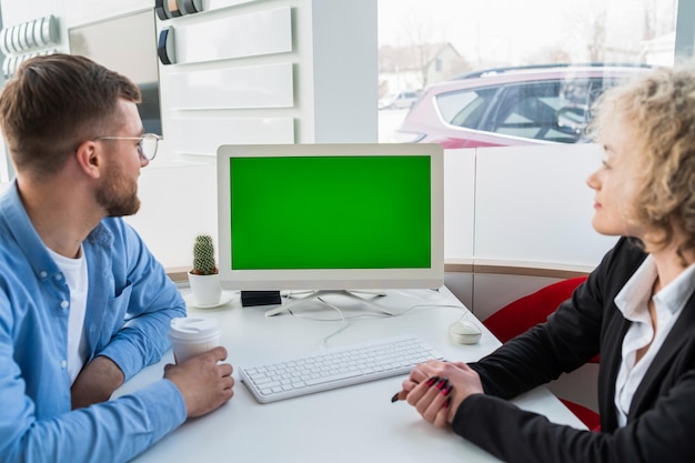 Autoverkoopmanager met klant bij computer in dealership