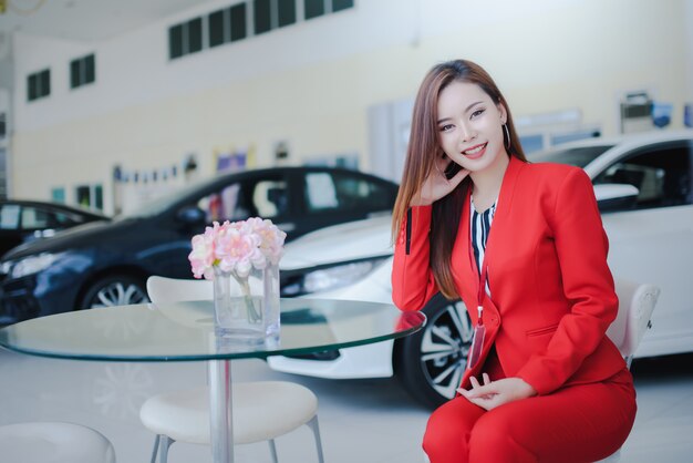 Autoverkopers, mooie vrouwen, Aziatische vrouwen die met klanten aan de telefoon zitten om nieuwe auto's in autoshowrooms te verkopen