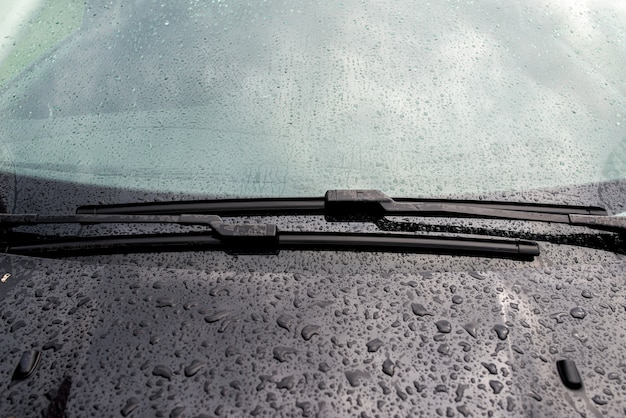 Autovoorruit met regendruppels en frameloze wisser close-up.