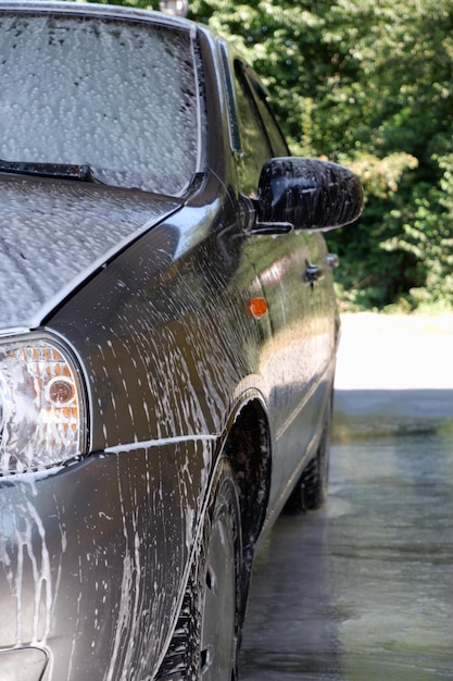 Autowas met een drukwasmachine De zijkant van de auto is bedekt met schuim