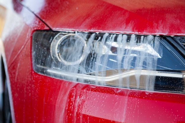 Autowassen close-up. Wassen moderne auto door water onder hoge druk met zeep