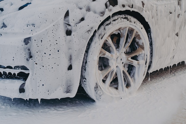 Autowiel in wit zeepschuim bij carwash-servicestation