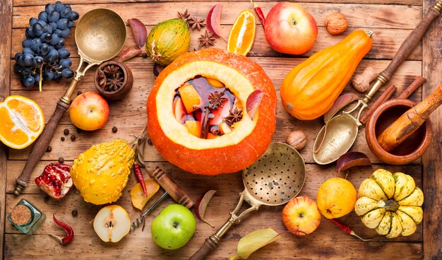 Autumn alcoholic drink mulled wine in pumpkin on wooden table