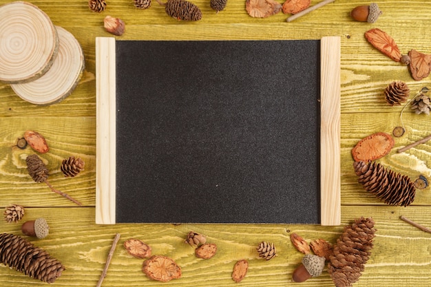 Autumn background. flat lay. pieces of wood, cones, acorns and a Board with space for text on a green grunge wooden background