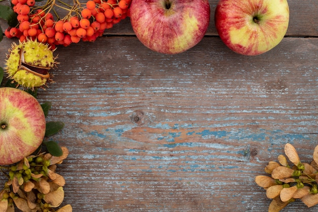 Foto sfondo autunnale da foglie cadute e frutti con impostazione di posto vintage sul vecchio tavolo in legno. concetto di giorno del ringraziamento.