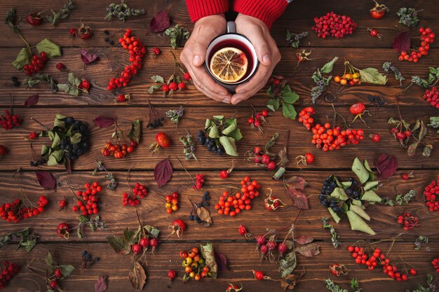 Photo autumn background. tea with lemon, berries and leaves on a wooden table.