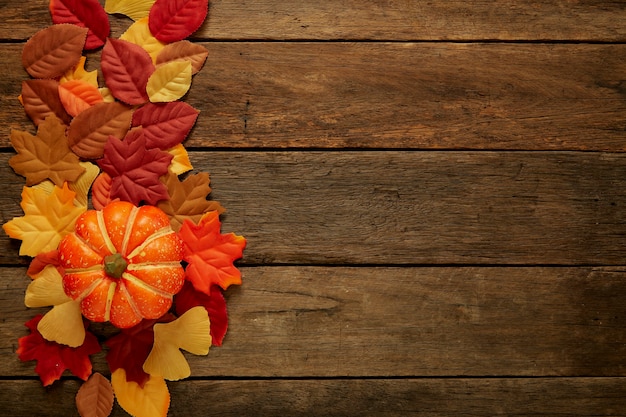 Autumn background with leaves and pumpkins on dark wooden