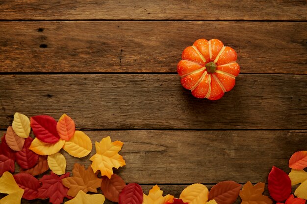 Autumn background with leaves and pumpkins on dark wooden