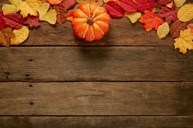 Sfondo autunno con foglie e zucche su legno scuro