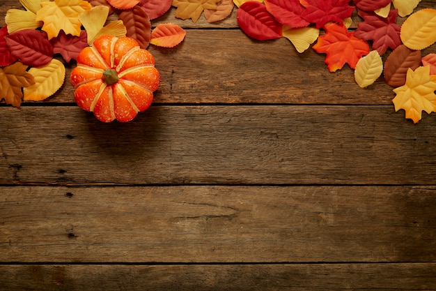 Autumn background with leaves and pumpkins on dark wooden