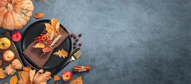 Autumn background with a plate with cutlery on a graphite background