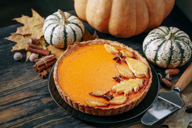 Autumn baking background with pumpkin pie pumpkin yellow autumn leaves on wooden background