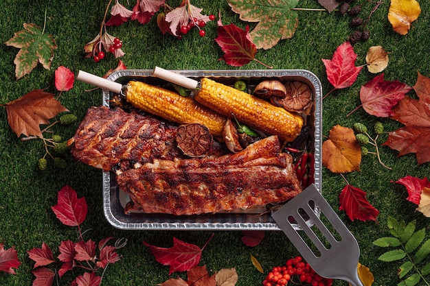 Foto barbecue autunnale costolette di maiale alla griglia mais e peperoni grigliati aglio al forno concetto di festa alla griglia autunnale giorno del ringraziamento raccolto autunnale