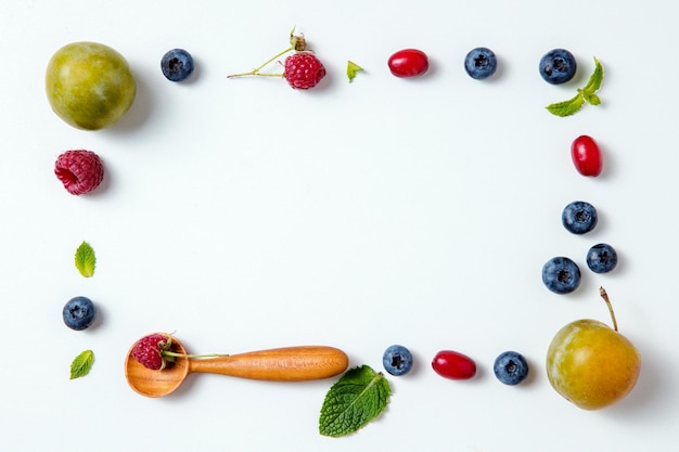 Autumn berries and wooden spoons on a white surface