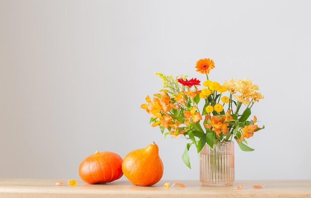 Autumn bouquet and orange pumpkins on wooden shelf on background gray wall
