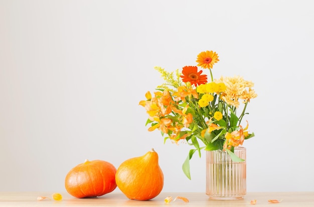 Autumn bouquet and orange pumpkins on wooden shelf on background gray wall