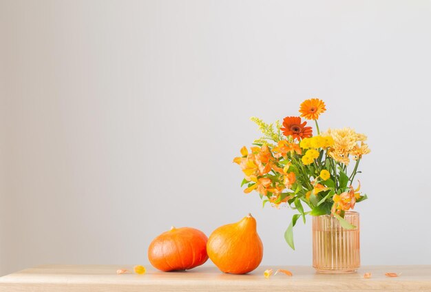 autumn bouquet and orange pumpkins on wooden shelf on background gray wall