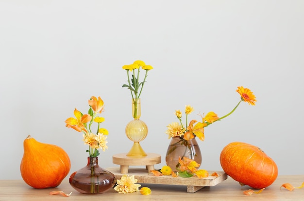 autumn bouquet and orange pumpkins on wooden shelf on background gray wall