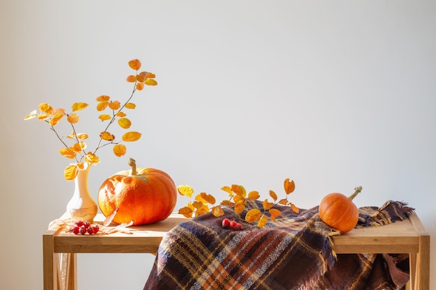 Autumn branches with orange leaves in vase and pumpkins on white background