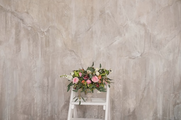 Autumn bridal bouquet of flowers stands on on the white staircase stepladder side view