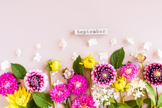 Autumn bright cut flowers in a floral composition on a beige background flat lay top view wooden calendarSeptember