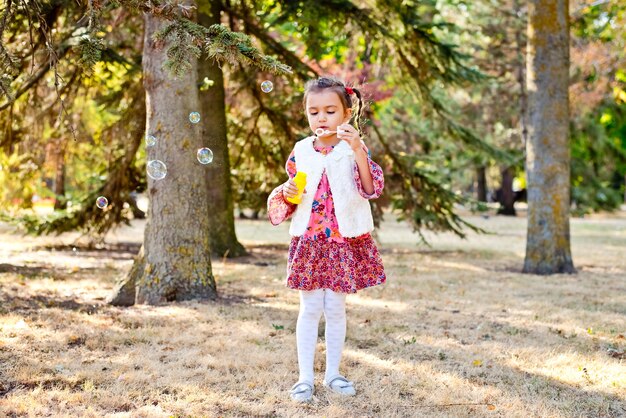 Autumn Cheerful little girl blowing soap bubbles