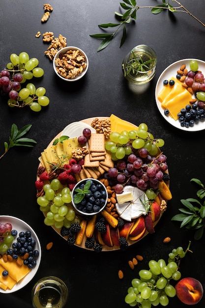 Autumn cheese board with fresh fruits nuts and berries served with white wine top view